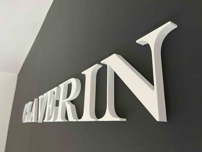Conception et installation d’une enseigne murale en lettres PVC laquées blanches 165 mm de hauteur sur 1600 mm de longueur et d’une enseigne drapeau aluminium dibond 600×400 mm à Marseille